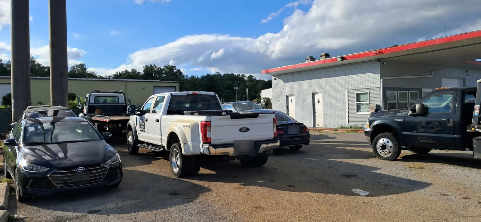 CM Towing flatbed trucks and a work pickup parked at the yard.
